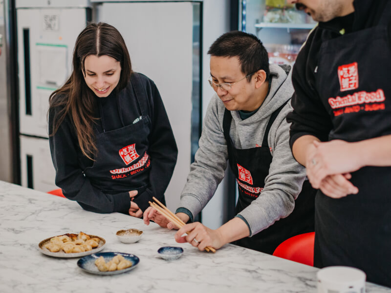 A Chinese cooking teacher demonstrating how to make dumplings